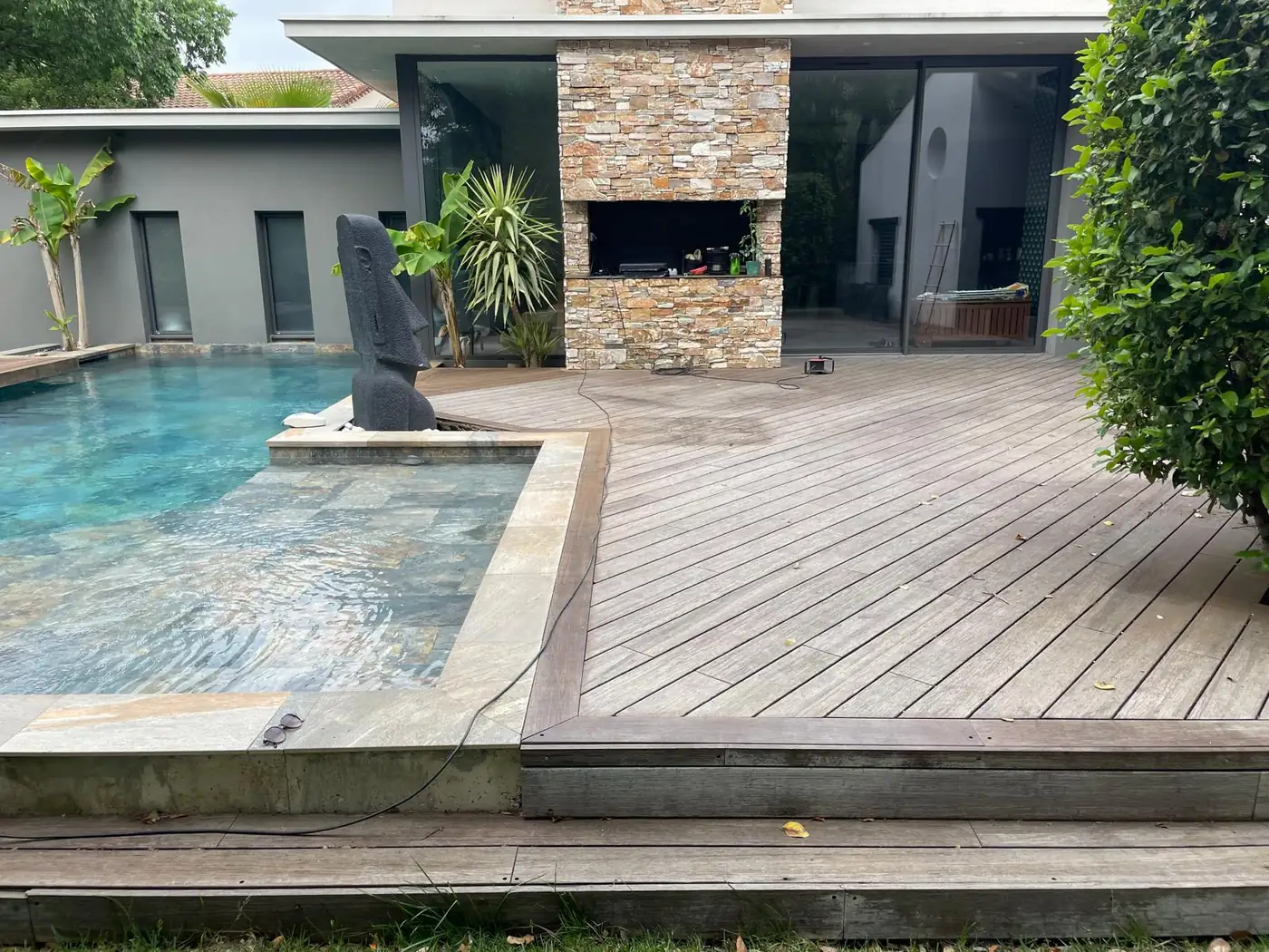 Terrasse en bois au bord d'une piscine, devant la maison