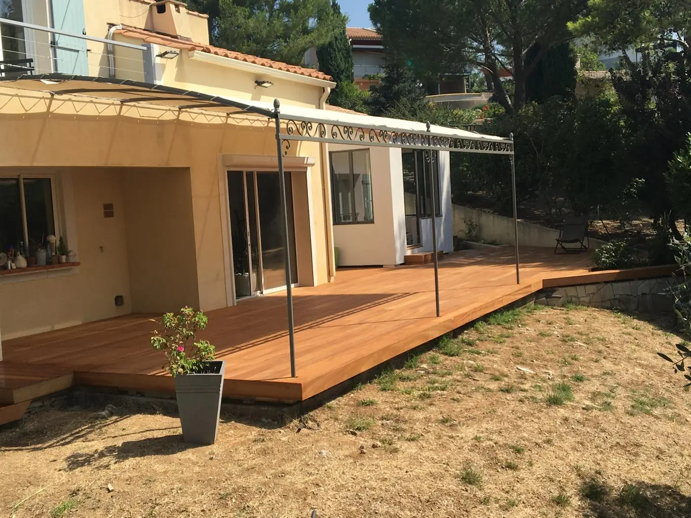 Terrasse en bois devant une maison, sous une pergola